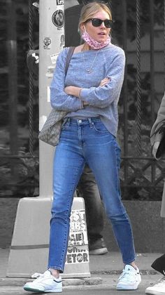 a woman in blue jeans is standing on the street