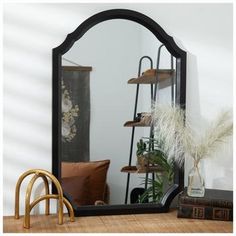 a mirror sitting on top of a wooden table next to a vase and potted plant