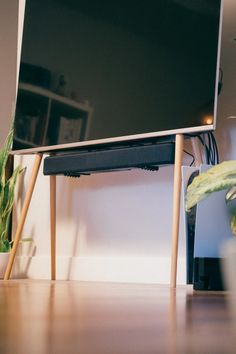 a flat screen tv sitting on top of a wooden stand next to a potted plant