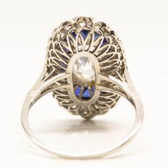 The Mila ring is a handmade engagement ring. It centers one antique oval very rare, elongated diamond of D color, SI2 clarity that weighs 1.72ctw. The center stone is surrounded by 22 natural calibrated French cut sapphires that weigh 2.50ctw. Thirty old mine cut diamonds of H color VS1 clarity that weigh 1.30ctw surrounded the sapphires in a second halo. This ring is currently size 8 and can be sized. Ring measurement: 23mm by 14mm Total weight: 3.9 dwt/ 6.1 grams Gia Certified Oval Sapphire Ring In Platinum, Classic Oval Multi-stone Cluster Ring, Classic Oval Cluster Ring With Multi-stone, Gia Certified Oval Platinum Ring, Oval Brilliant Cut Sapphire Ring, Oval Platinum Halo Ring With Gemstone, Platinum Oval Halo Ring With Gemstone, Art Deco Oval Sapphire Ring In Platinum, Art Deco Oval Sapphire Ring With Center Stone