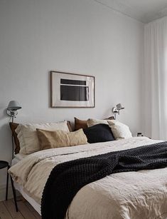 a bedroom with white walls and wooden flooring has a black blanket on the bed