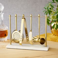 gold kitchen utensils and graters are on a white stand next to a potted plant