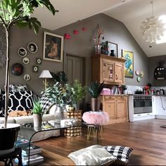 a living room filled with furniture and lots of plants on top of a hard wood floor