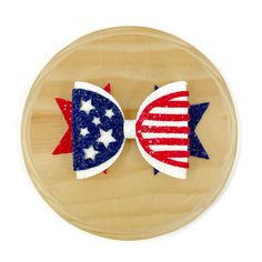 two red, white and blue bows with stars on them are sitting on a wooden plate