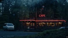 a restaurant with red neon lights on the side of it and a van parked in front