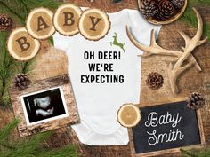 a baby bodysuit with the words oh deer we're expecting next to it