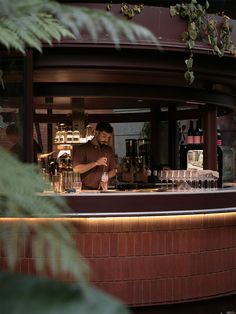 a man standing behind a bar making drinks