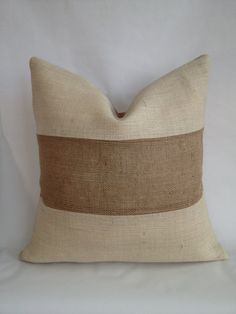 a beige and brown pillow on a white surface with a black stripe down the middle