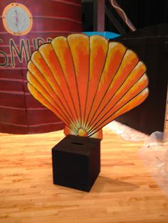 an orange shell is sitting on top of a black block in the middle of a wooden floor