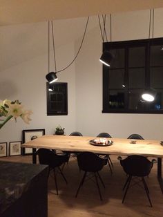 a dining room table with black chairs and white flowers