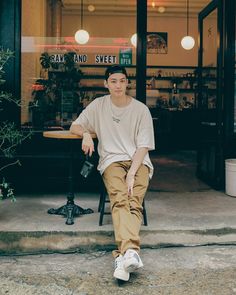 a young man sitting on the steps in front of a store