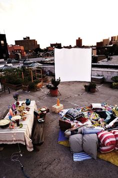 an outdoor movie is set up in the middle of a rooftop with lots of furniture