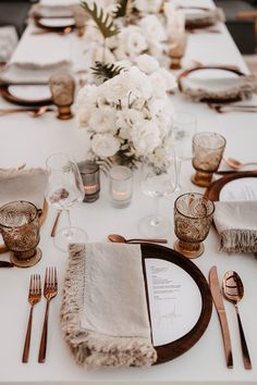 the table is set with white flowers and silverware