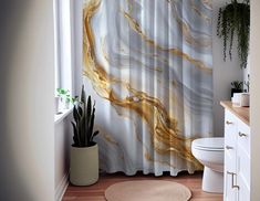 a white toilet sitting next to a bathroom sink under a shower curtain with gold leafy designs on it