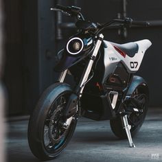 a white and black motorcycle parked in front of a garage door with the number 70 on it's side