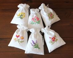 six bags with embroidered flowers on them sitting on a wooden floor next to each other