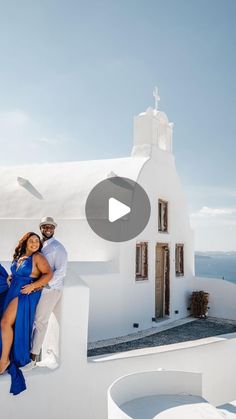 a man and woman posing for a photo in front of a white building with blue shutters