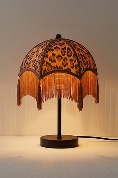 a leopard print lamp with fringes on the base and a light shade over it