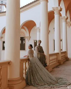 two people standing next to each other in front of some pillars and columns with arches