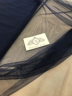 a piece of cloth with a label on it sitting on a bed sheet that is covered in sheer fabric