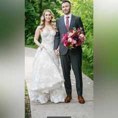 a bride and groom holding hands on a path in front of some trees at their wedding