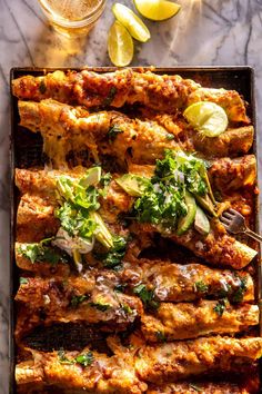 an overhead view of some food on a tray with lemons and lime wedges