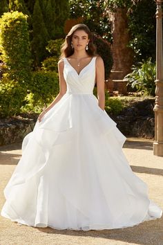 a woman in a white wedding dress posing for the camera with her hand on her hip