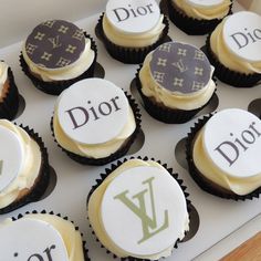 cupcakes decorated with the names of many famous brands are displayed in a box