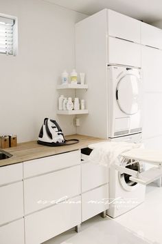 a laundry room with white cabinets and washer and dryer on the counter top