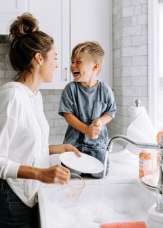 a woman standing next to a little boy in a kitchen