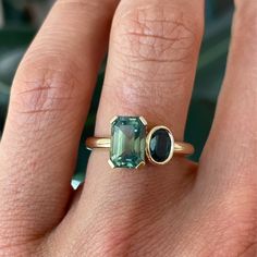 a woman's hand with a ring and an emerald stone on it, next to her finger