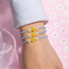 a woman's hand with three bracelets decorated with smiley faces