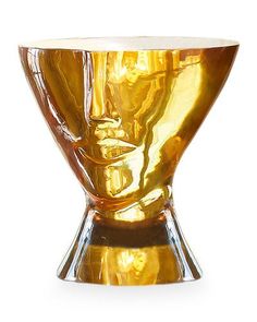 a gold colored vase sitting on top of a white table