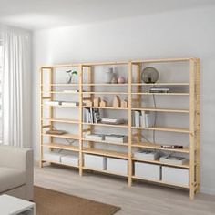 a living room filled with furniture next to a white wall mounted book shelf on top of a hard wood floor