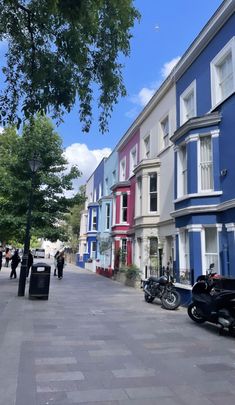 a row of multi - colored buildings on a city street with motorcycles parked in front