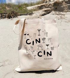 a tote bag with the words cin on it is sitting in the sand