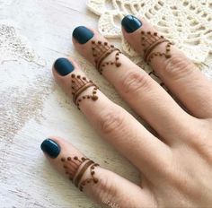 two fingers with henna tattoos on them