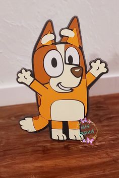 an orange and white cartoon cat standing on top of a wooden table next to a sticker