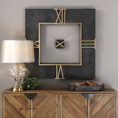 a large clock on the wall next to a sideboard with a lamp and basket