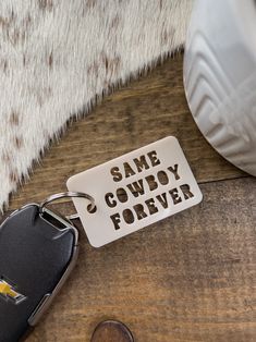 a keychain that says same cowboy forever on it next to a computer mouse