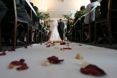 a bride and groom walking down the aisle at their wedding ceremony with rose petals on the floor