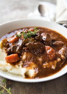 a white bowl filled with mashed potatoes and beef on top of gravy