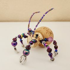 a wine cork and beaded spider on a white surface with a cork holder in the background