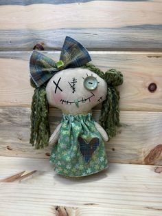 a creepy doll with green hair and blue eyes sitting on wooden planks in front of a wall