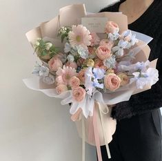 a woman holding a bouquet of pink and white flowers