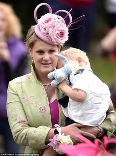 a woman holding a baby wearing a pink hat with flowers on it's head