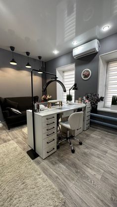 a white desk sitting on top of a hard wood floor next to a black couch