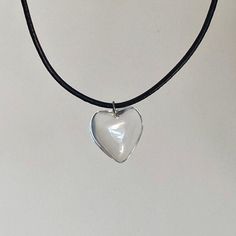 This clear heart cord necklace features a glass heart pendant on a black leather chain, representing coquette jewelry and making it a thoughtful gift idea for women who appreciate unique heart necklaces. 𝐃𝐄𝐓𝐀𝐈𝐋𝐒:  ⭐️ Necklace length is 18" + 2" extender  ⭐️ Heart Pendant size is 20mm, 8mm thick ⭐️ The clear heart charm is clear glass & the chain is a leather black cord  ⭐️ Ideal for a simple everyday necklace or gift for her, The Vacant Heart necklace  ⭐️ ALL jewelry include 1 year warran Clear Heart Charm Necklace With Heart Pendant, Clear Heart Charm Necklace, Clear Glass Heart Pendant Necklace, Necklace Coquette, Coquette Jewelry, Clear Heart, Black Leather Necklace, Heart Necklaces, Everyday Necklace