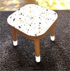 a small wooden stool sitting on top of a black rug