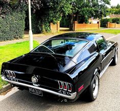 a black muscle car parked on the side of the road